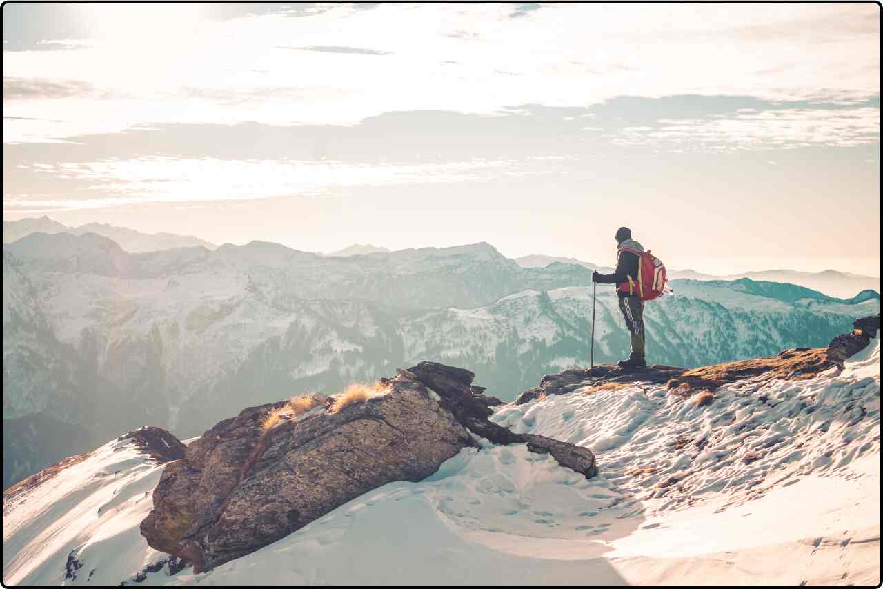 An adventurer enjoying the scenic vista from a snow-capped mountain in India.